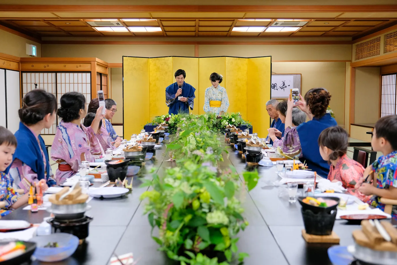 旅館の宴席で、ゲストと食卓を囲むふたり