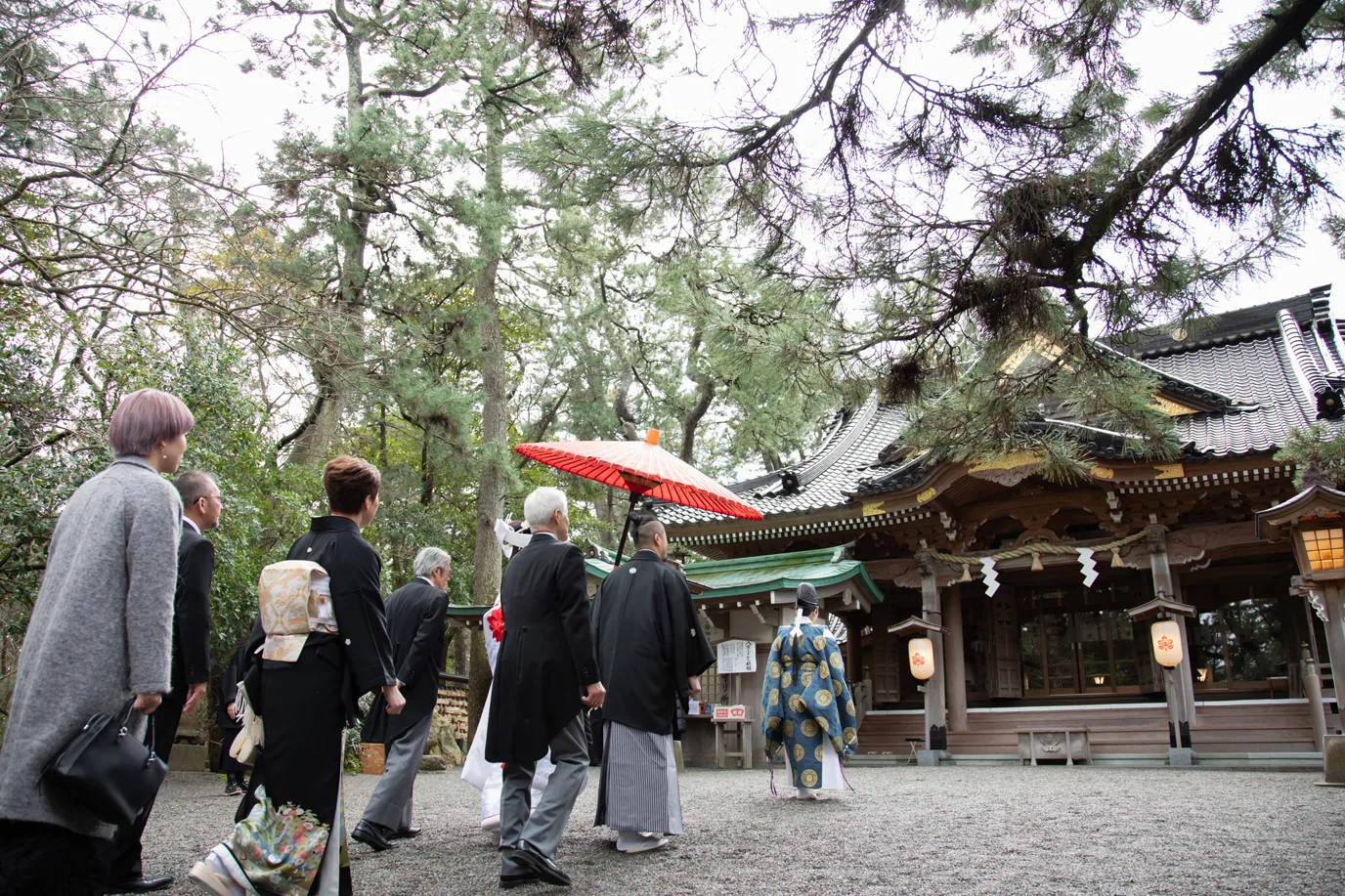 神前式のため神社の境内を進む新郎新婦と参列者