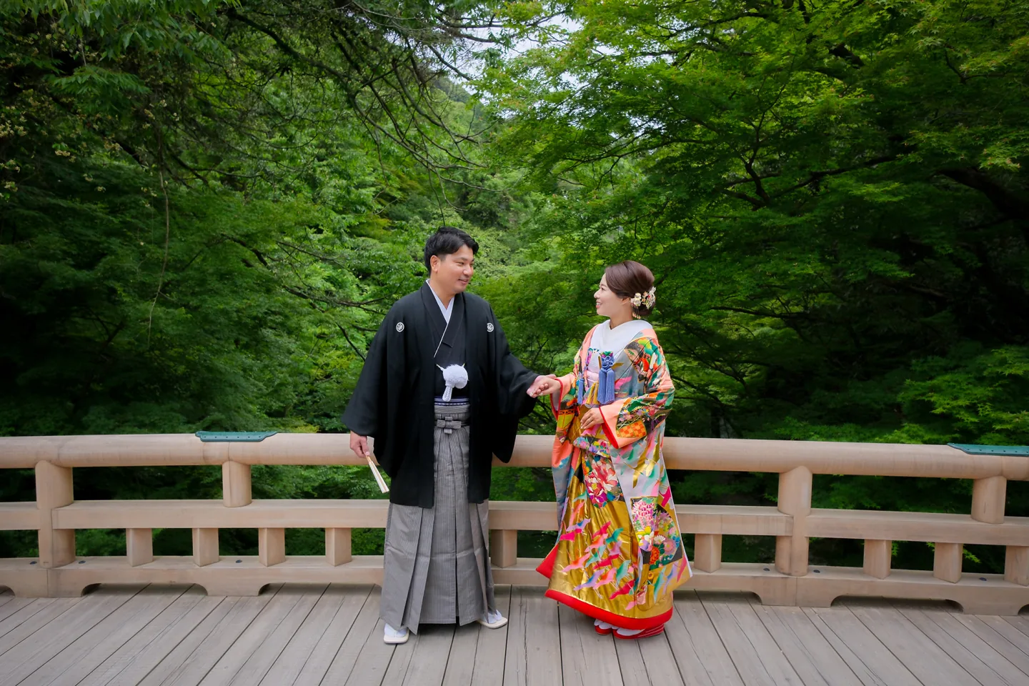 山中温泉の緑に囲まれた橋に立つ和装のふたり